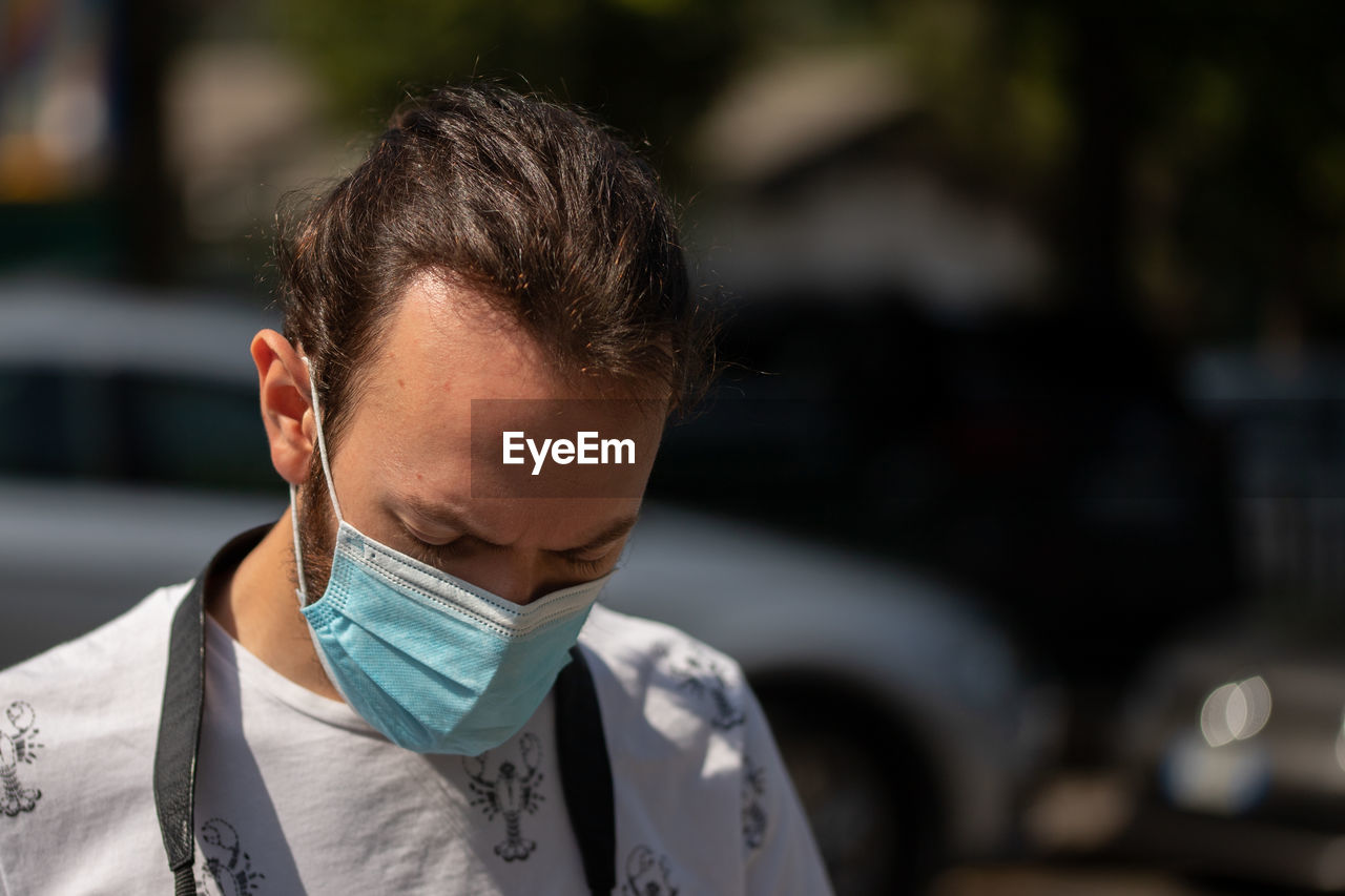 Close-up portrait of young man outdoors with surgical mask. covid 19 concept