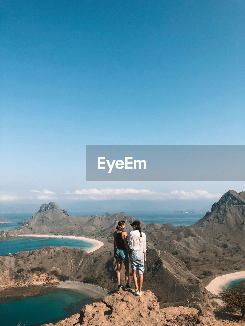 Full length of women standing on mountain against blue sky