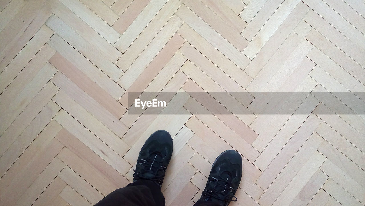 HIGH ANGLE VIEW OF MAN STANDING ON HARDWOOD FLOOR