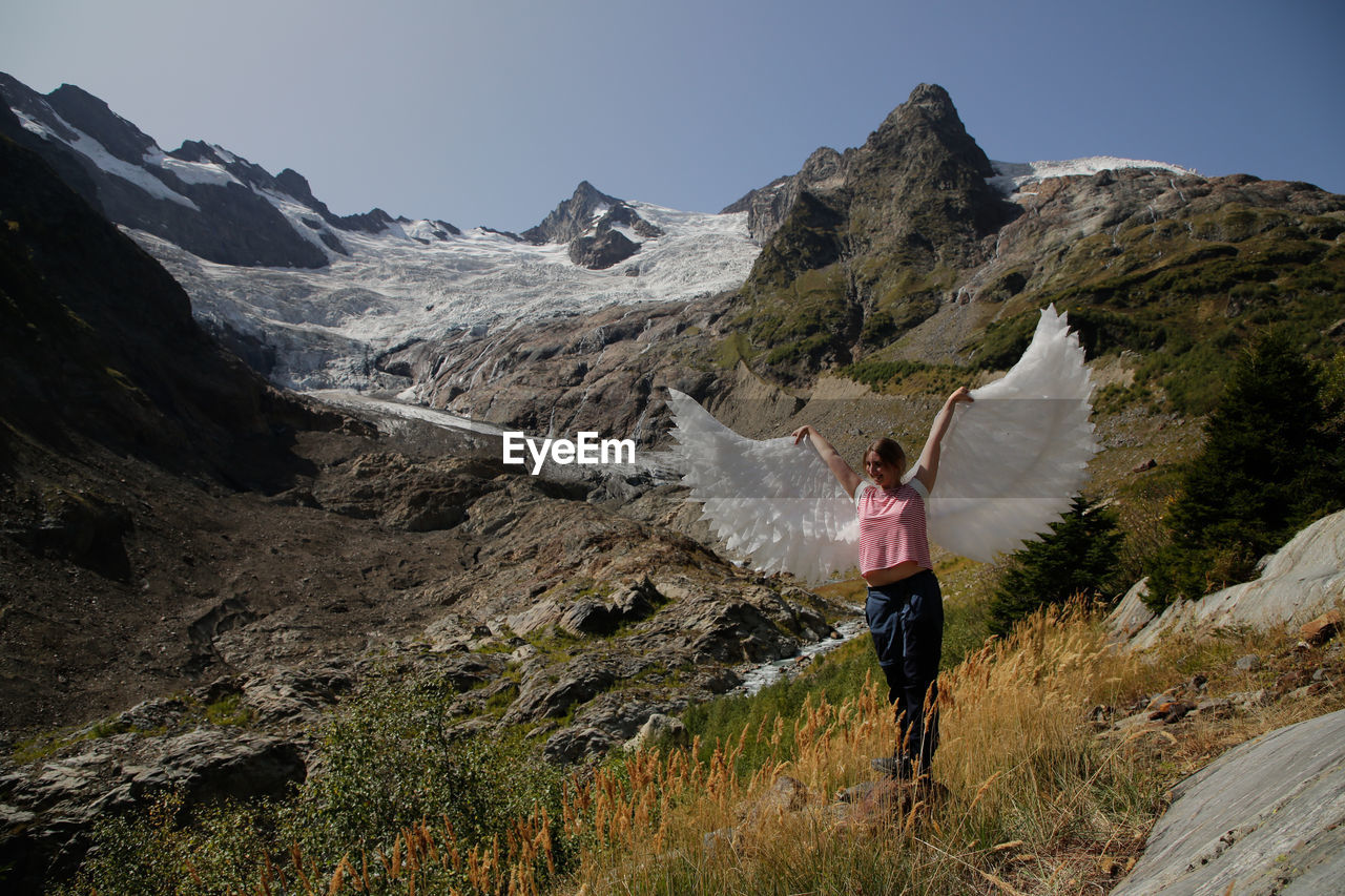 MAN STANDING ON MOUNTAINS AGAINST SKY