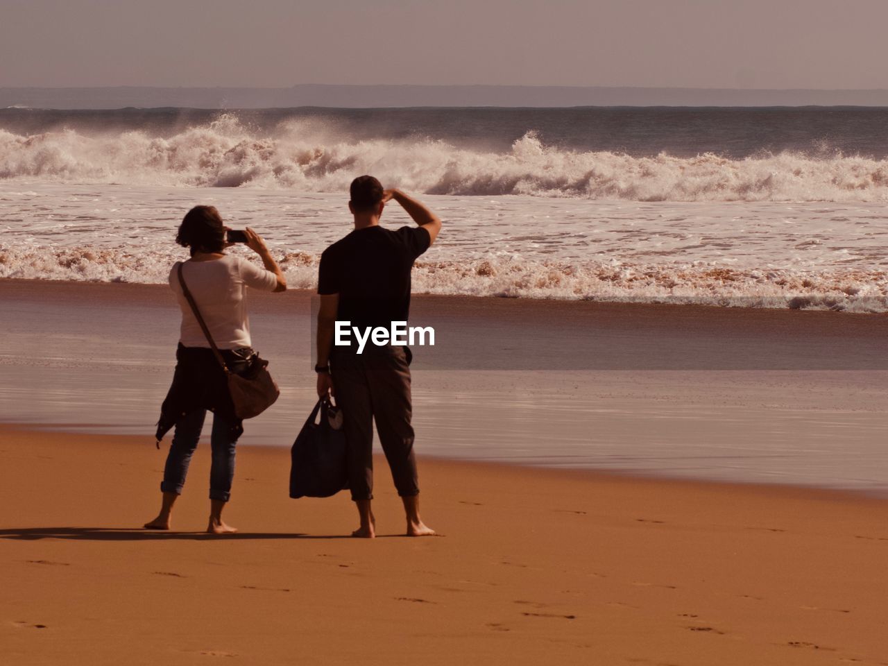 REAR VIEW OF TWO PEOPLE ON BEACH