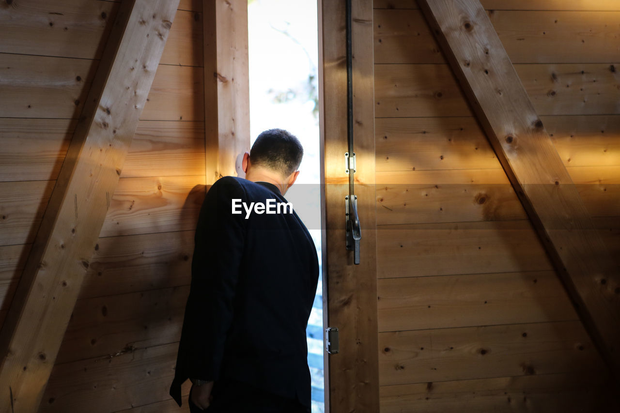 REAR VIEW OF A MAN STANDING IN CORRIDOR OF A PERSON