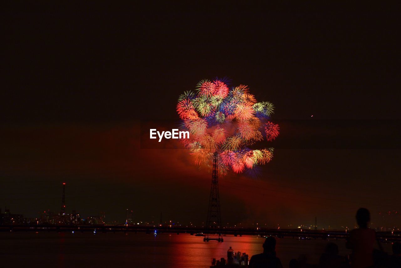 Low angle view of firework display over cityscape at night