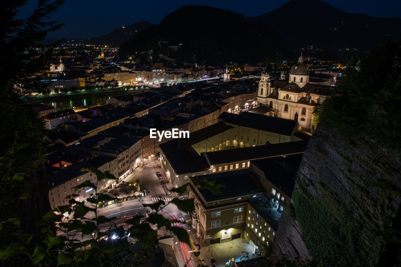 HIGH ANGLE VIEW OF ILLUMINATED BUILDINGS AT NIGHT