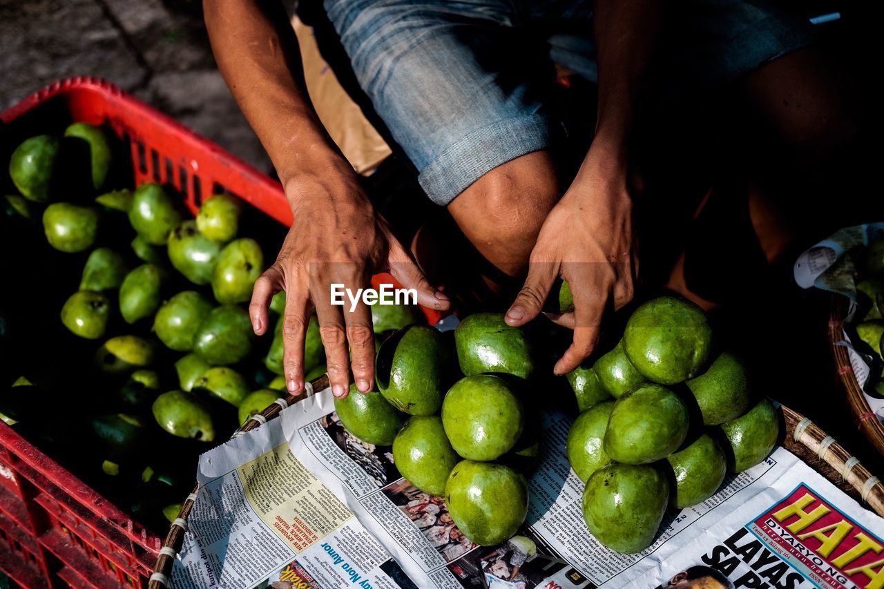 Midsection of vendor selling fruits at market on sunny day