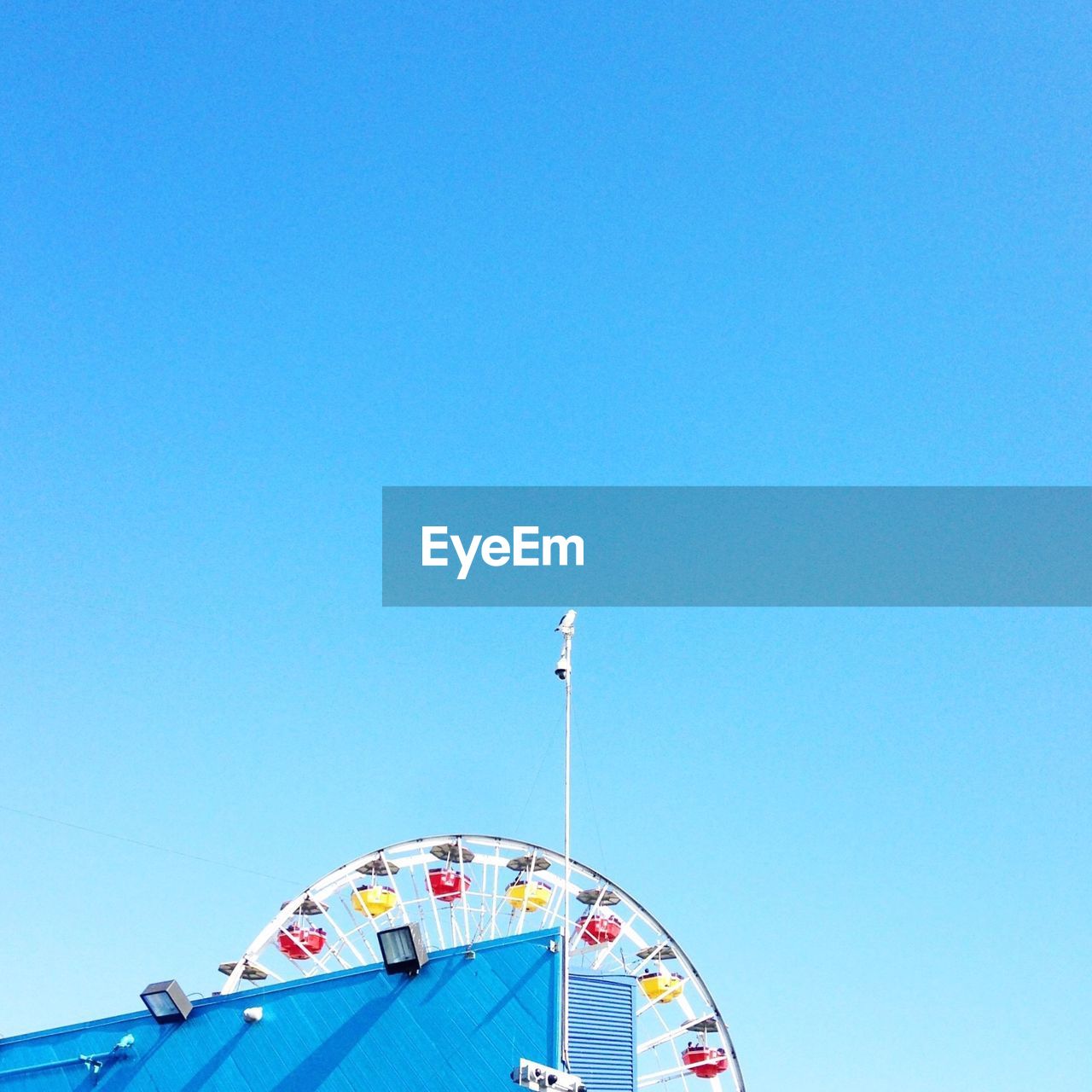 LOW ANGLE VIEW OF CAROUSEL AGAINST CLEAR BLUE SKY