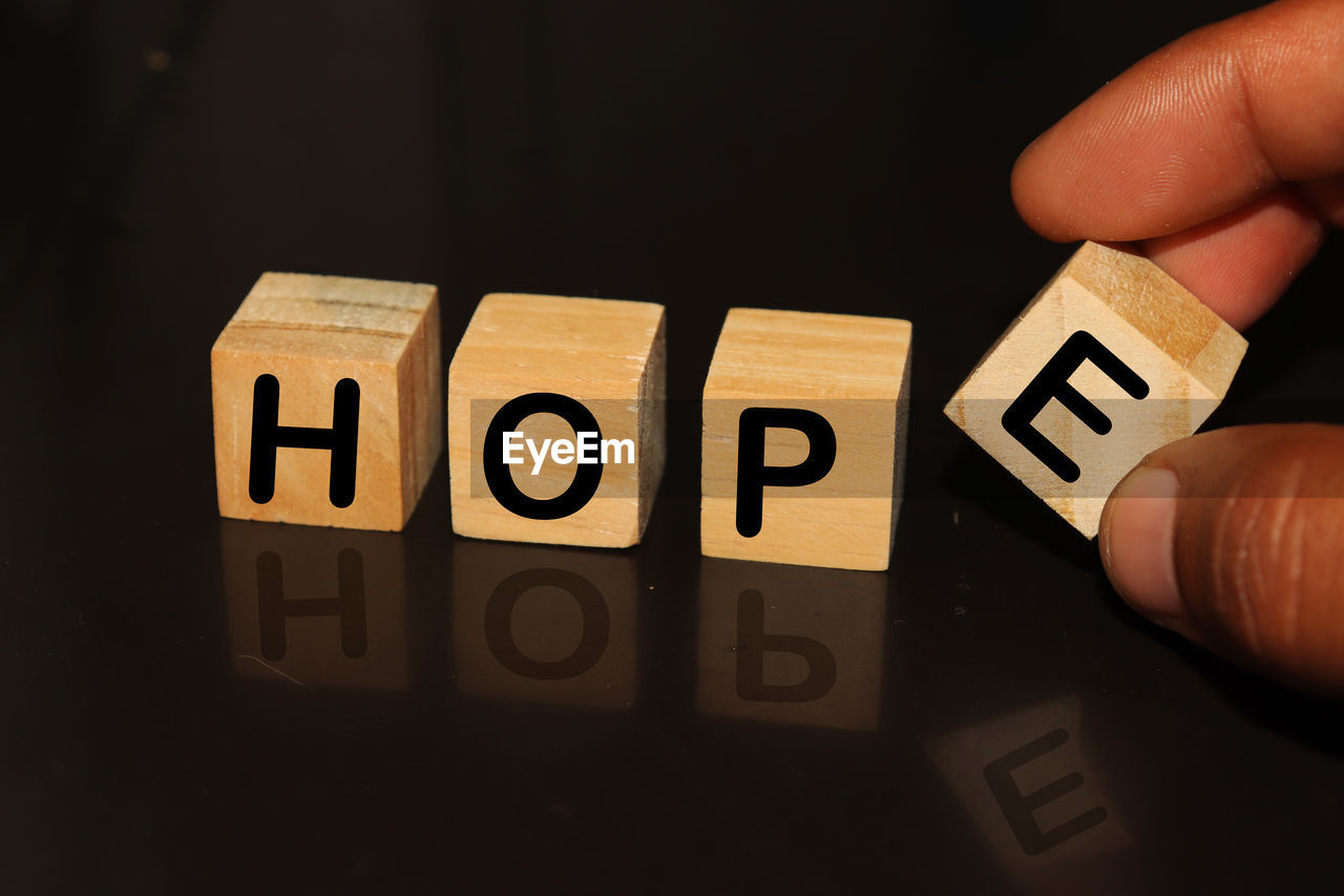 Cropped hand with hope text on toy blocks against black background