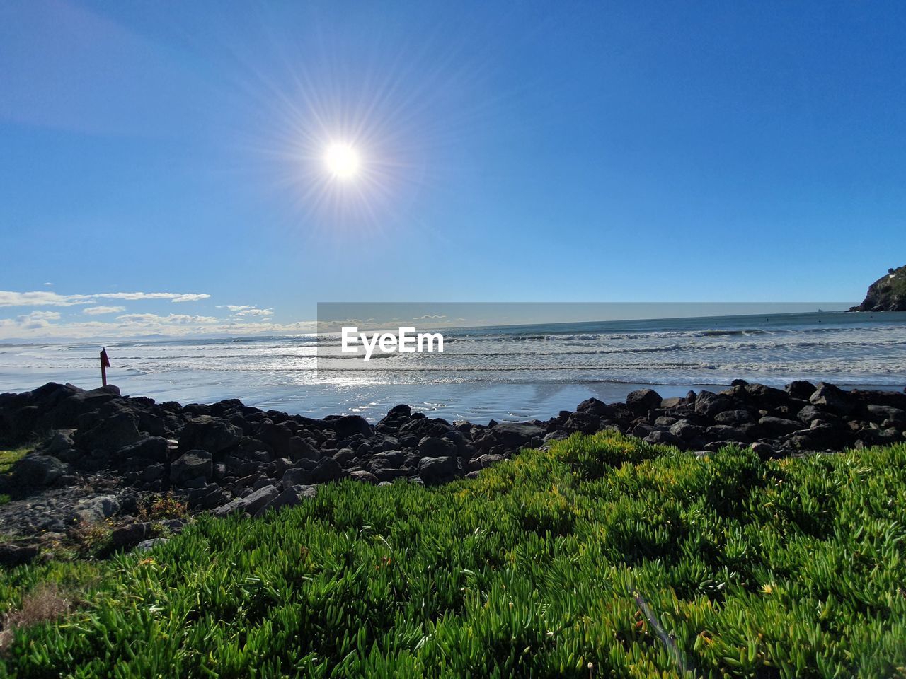 SCENIC VIEW OF BEACH AGAINST BRIGHT SUN