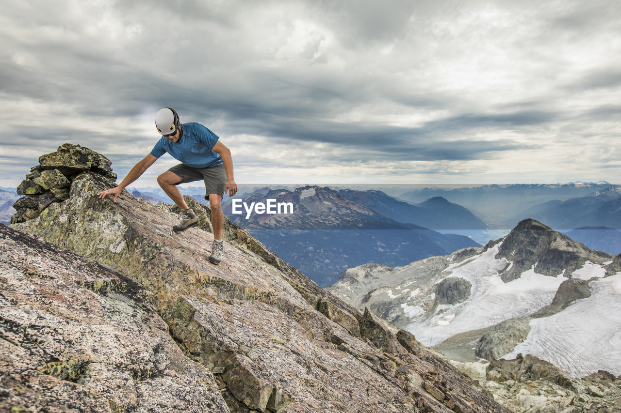 Climber carefully hikes off the summit of a mountain.