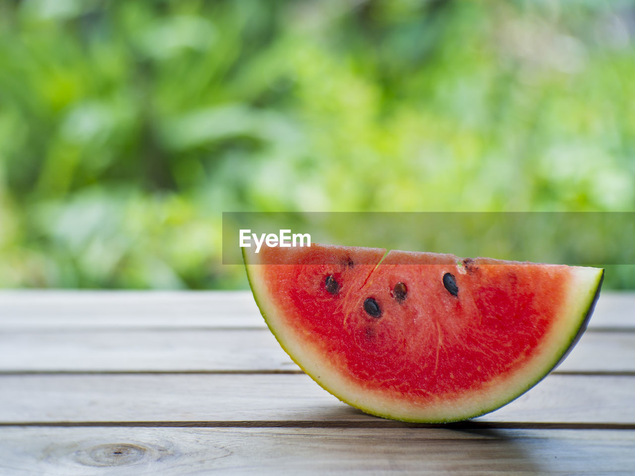 CLOSE-UP OF APPLE ON TABLE AGAINST BLURRED BACKGROUND