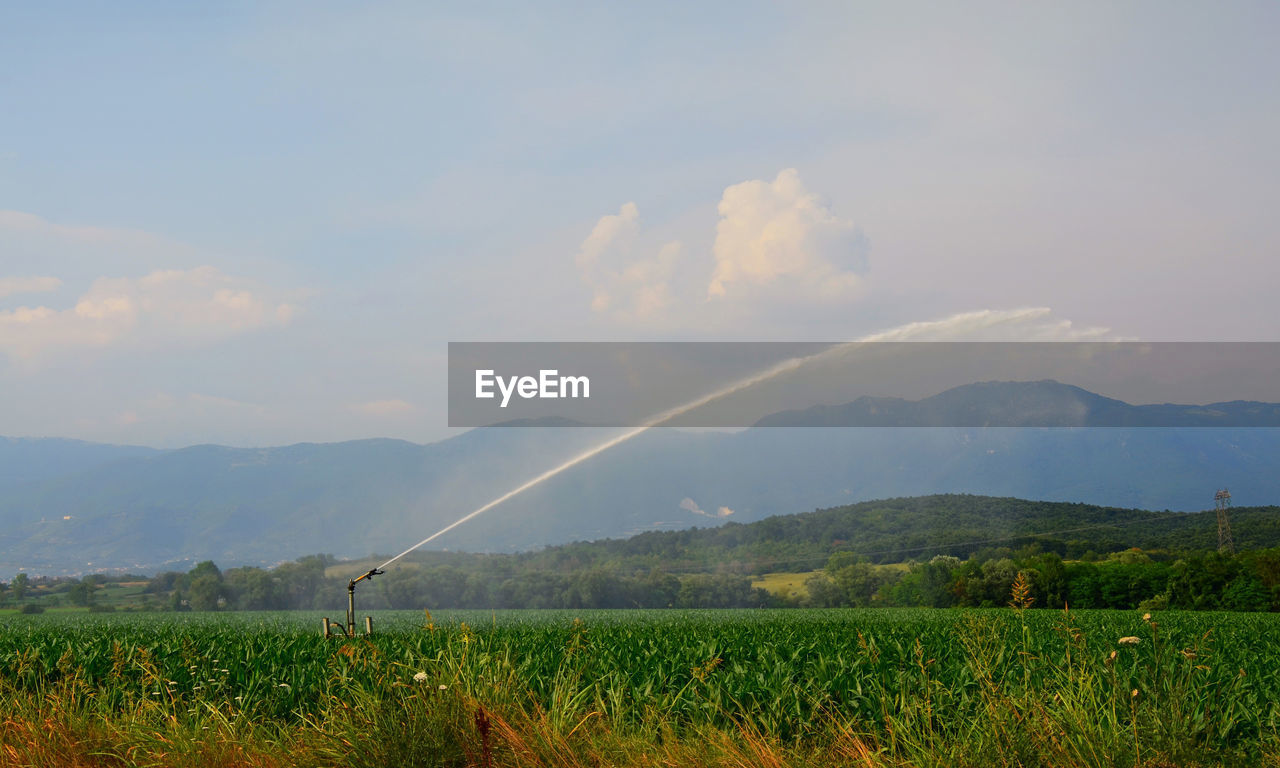 Agricultural sprinkler on landscape against sky