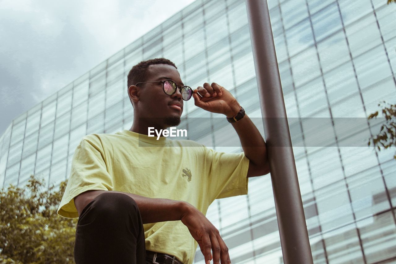 Low angle view of young man standing against building