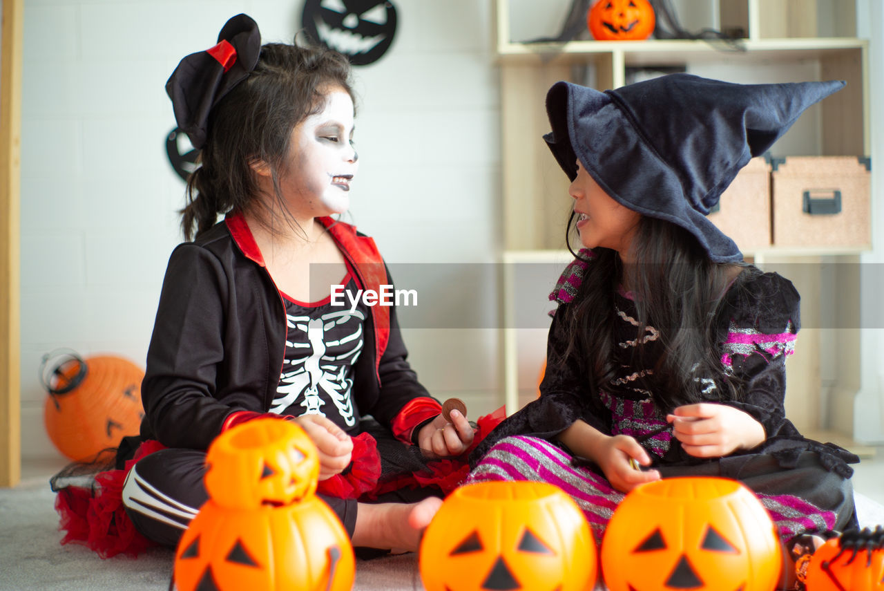 Smiling girls wearing costume sitting at home