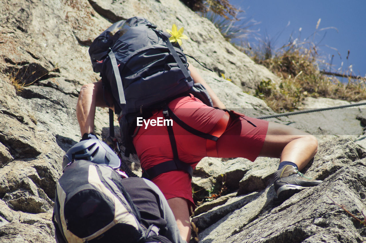 Rear view of man climbing on rock at via ferrata