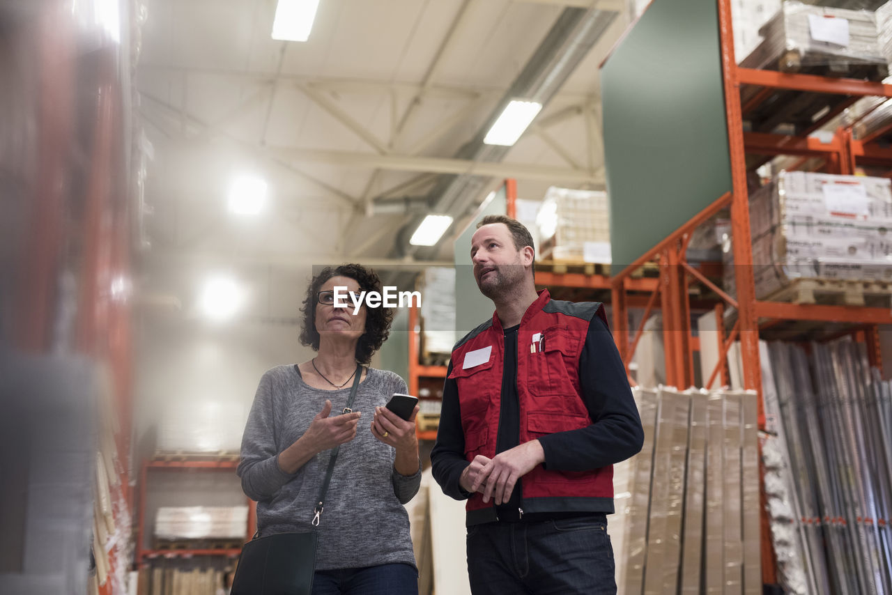 Customer holding smart phone while standing with salesman in hardware store