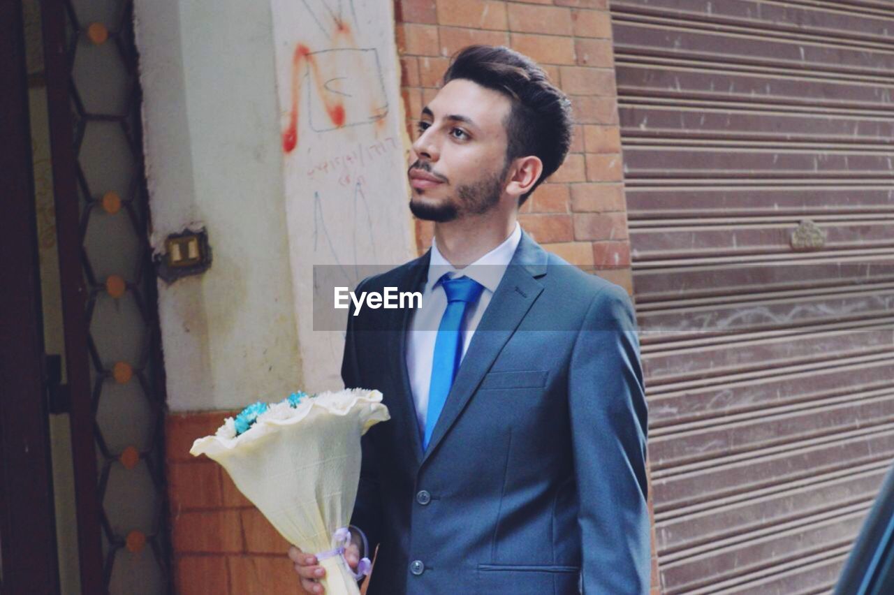 Smiling young man holding bouquet