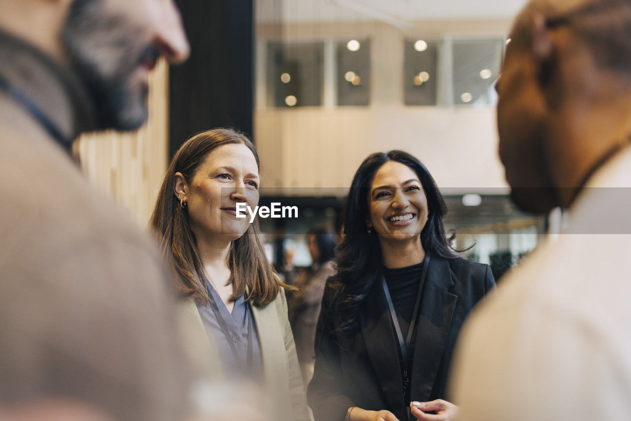 Female entrepreneurs talking with male delegates during networking event at convention center