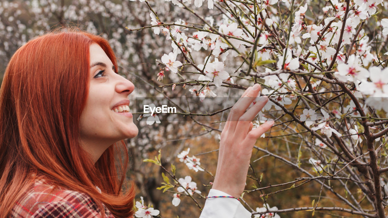 Happy red-haired girl under spring flower tree. spring mood.