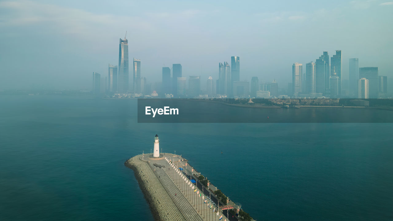 Modern buildings by sea against sky in city