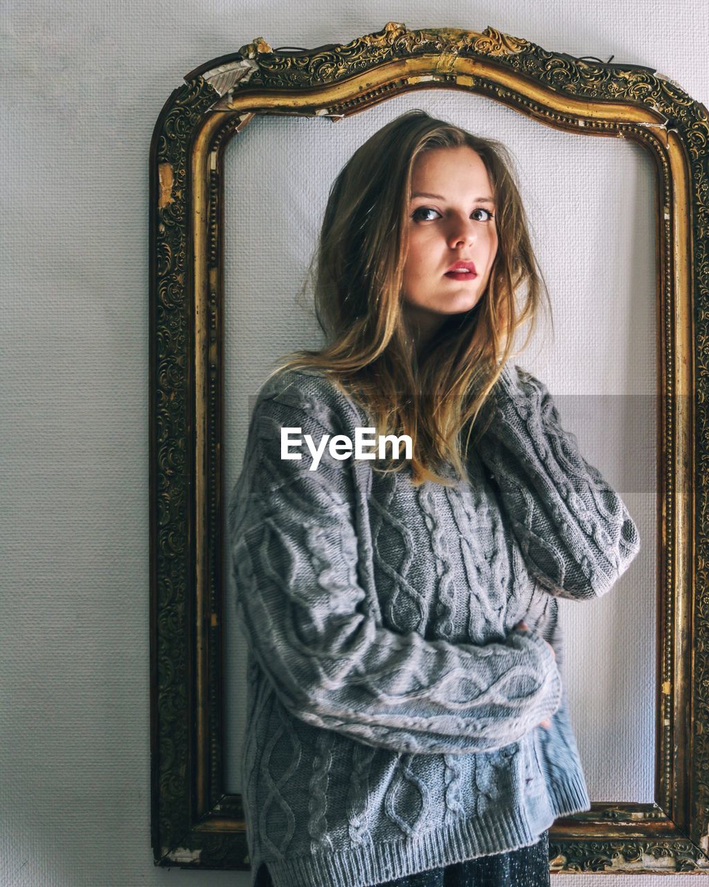 Young woman standing by frame at home