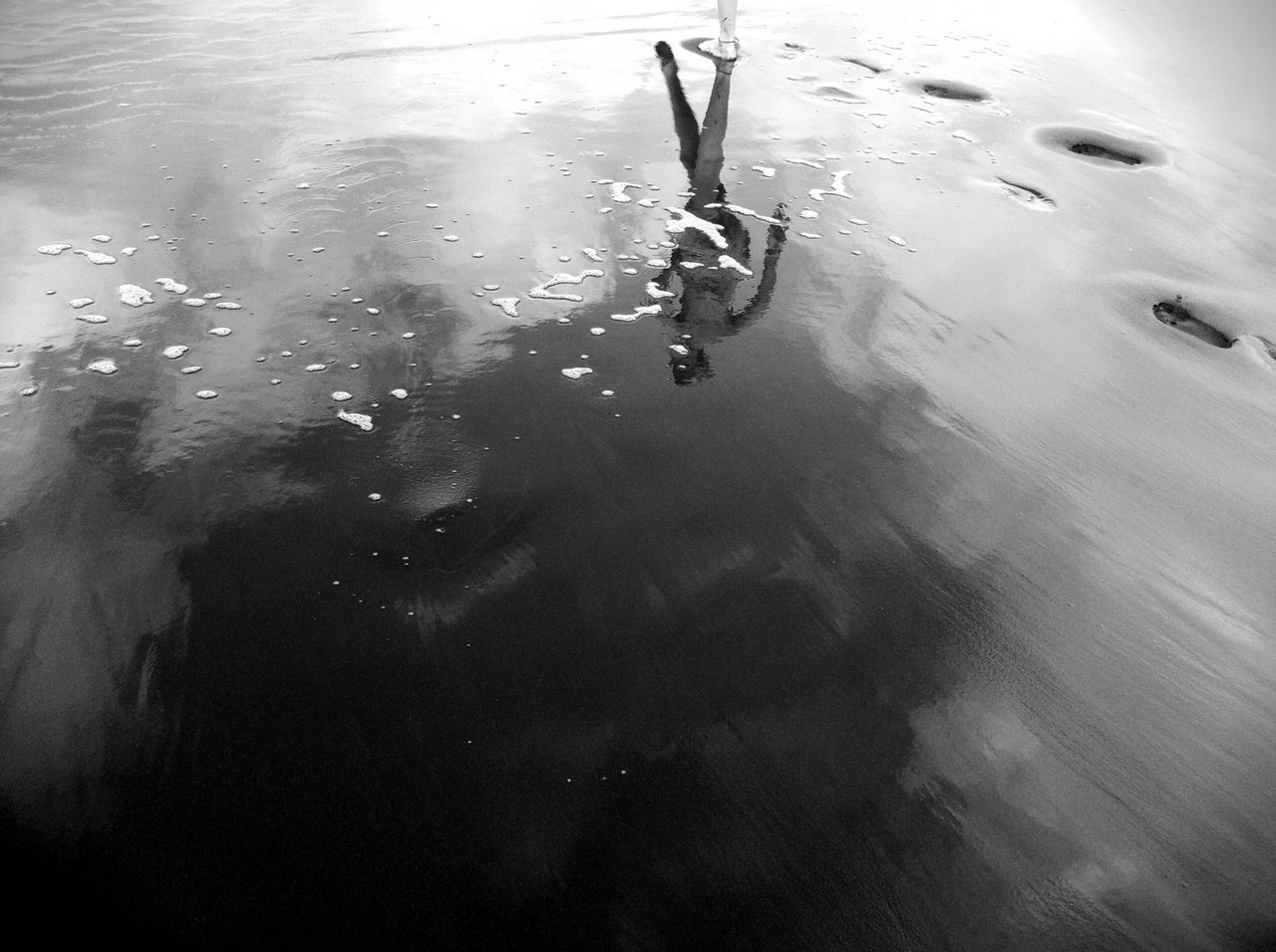 Reflection of woman on wet sand