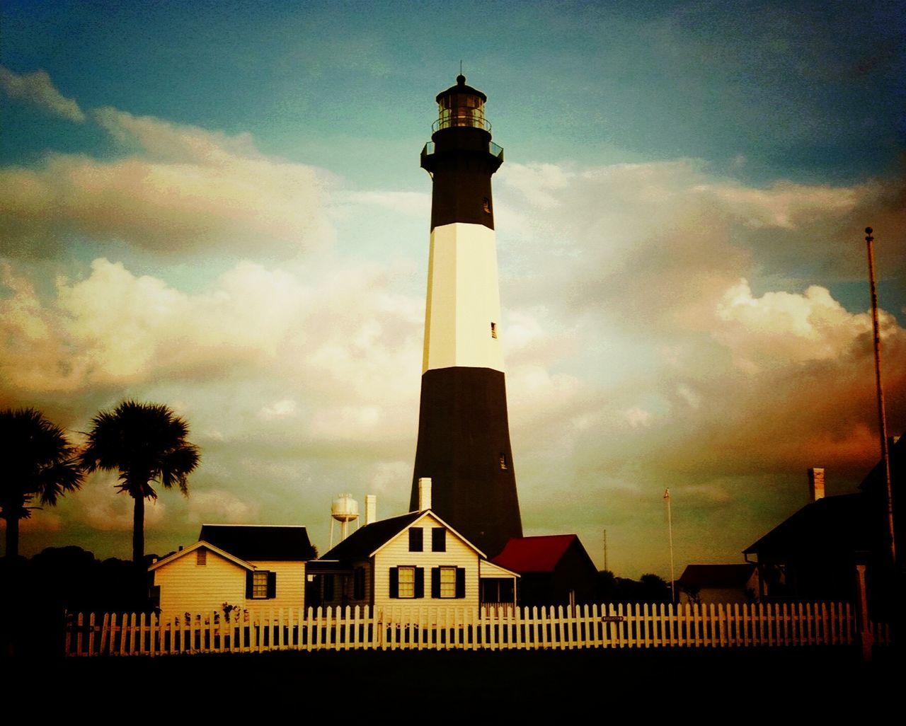 LOW ANGLE VIEW OF LIGHTHOUSE AGAINST CLOUDY SKY AT SUNSET