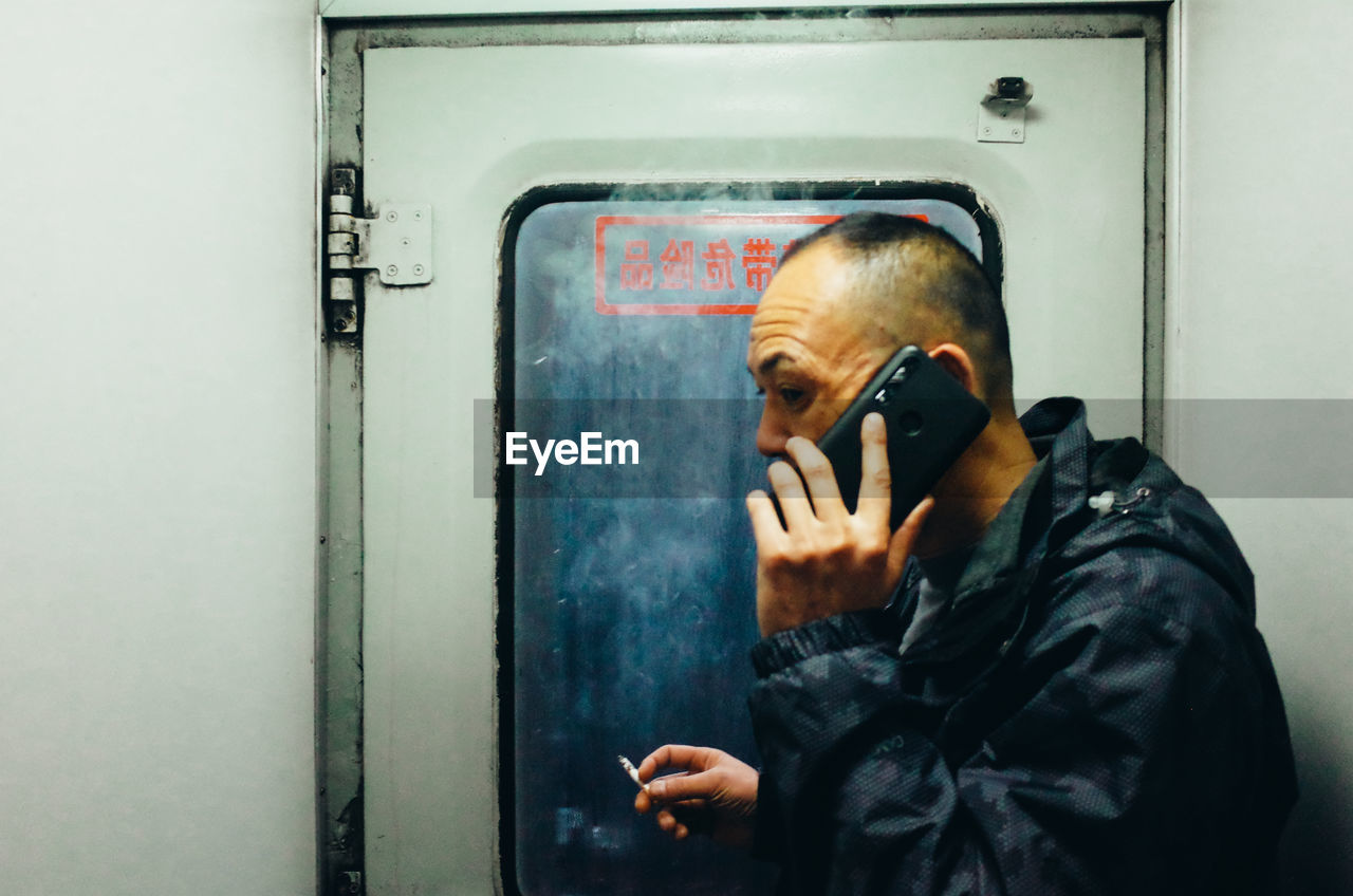 PORTRAIT OF MAN USING MOBILE PHONE IN OFFICE