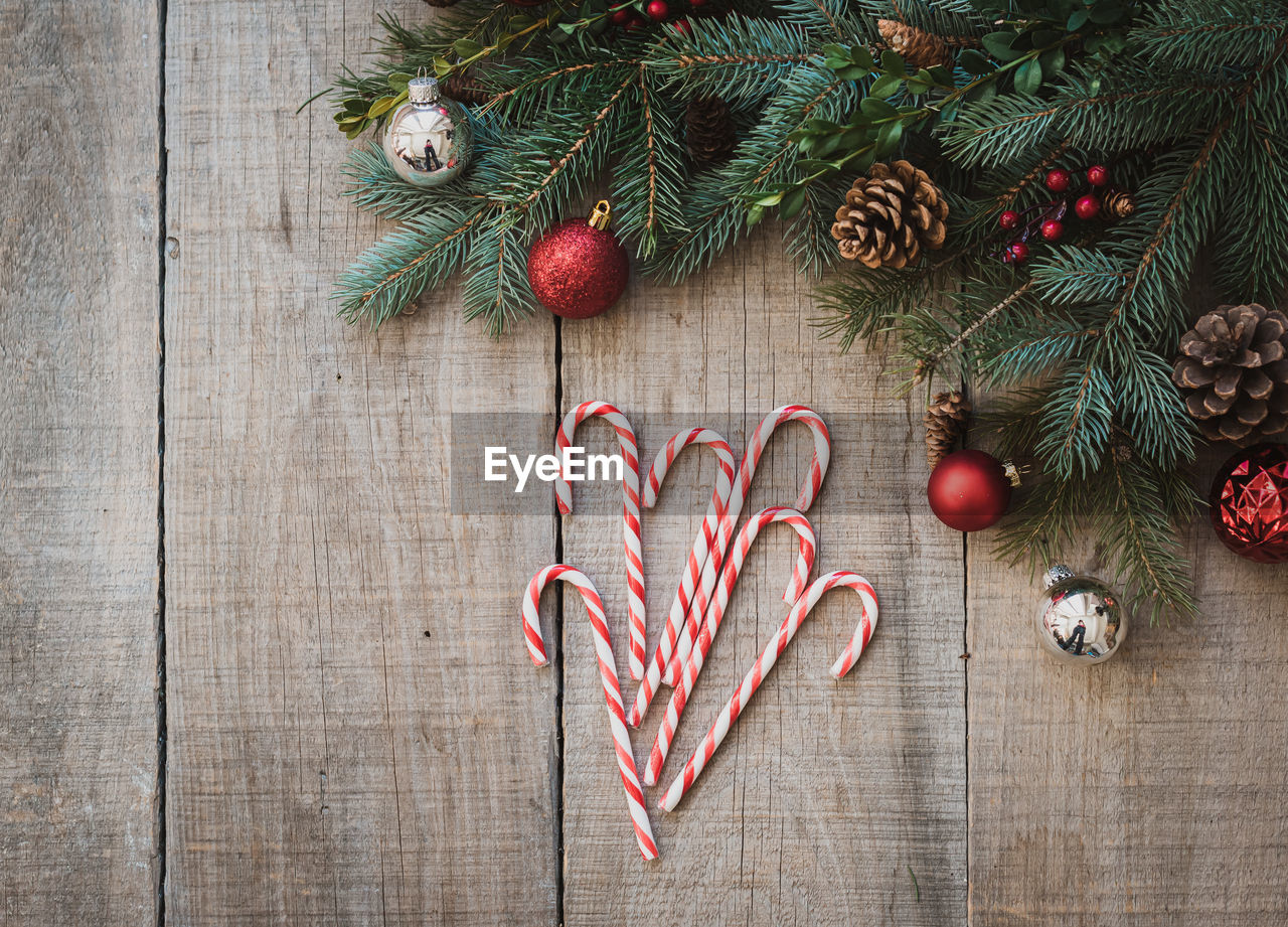 Candy canes on weathered wood table with christmas decor from above.