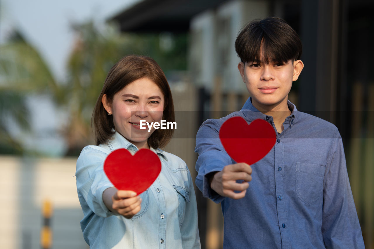 PORTRAIT OF HAPPY FRIENDS HOLDING HEART SHAPE