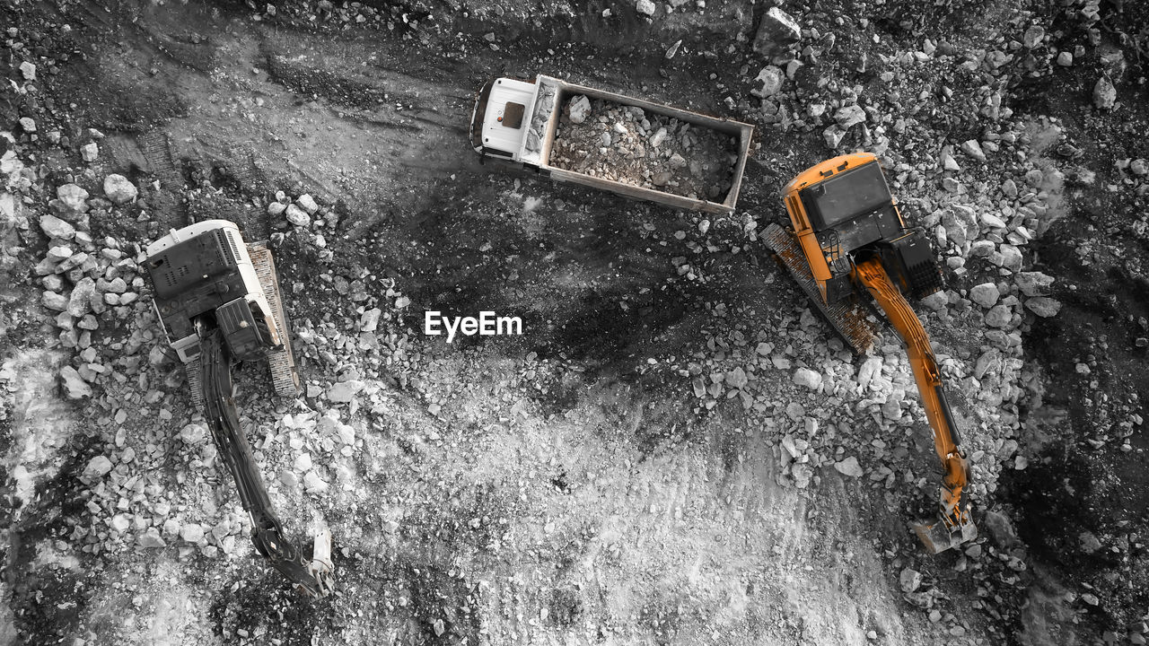 Top down aerial view of excavator loading tipper truck with crushed rock soil. 