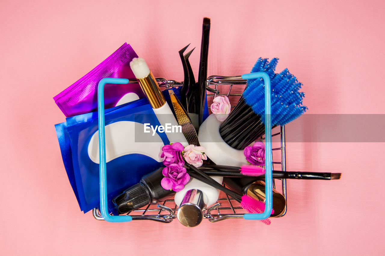 Eyelash extension kit in a small grocery basket on pink background. the concept of beauty.