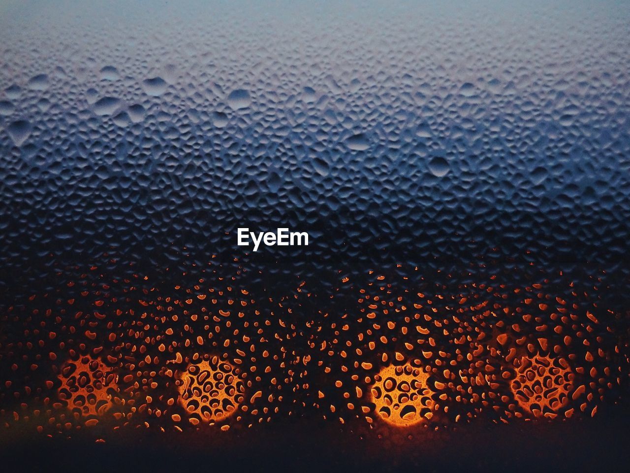 Close-up of waterdrops on glass against blurred lights