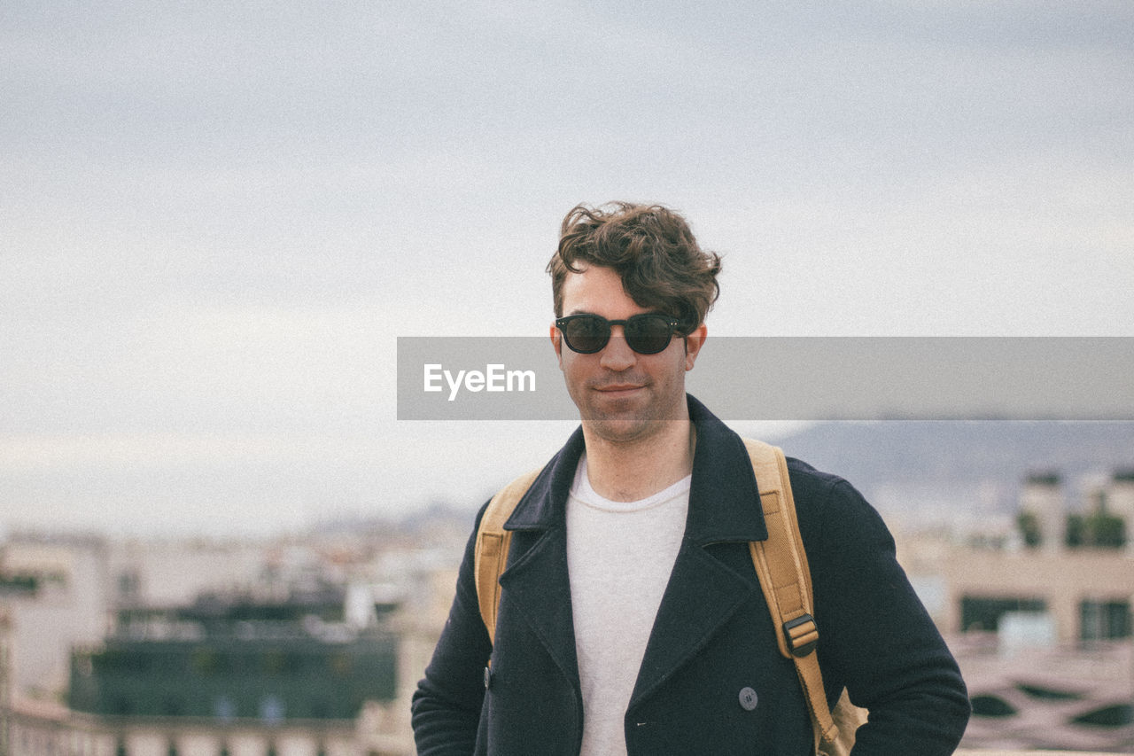 Portrait of man wearing sunglasses against cityscape