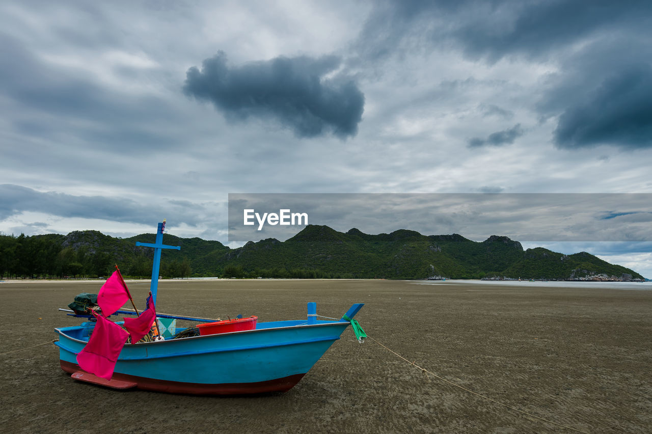 BOAT MOORED ON SHORE AGAINST SKY