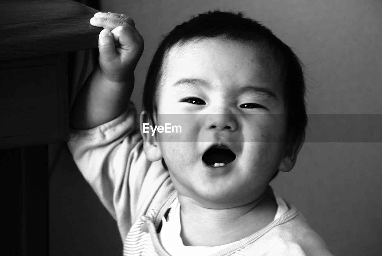 Close-up portrait of baby boy against wall at home