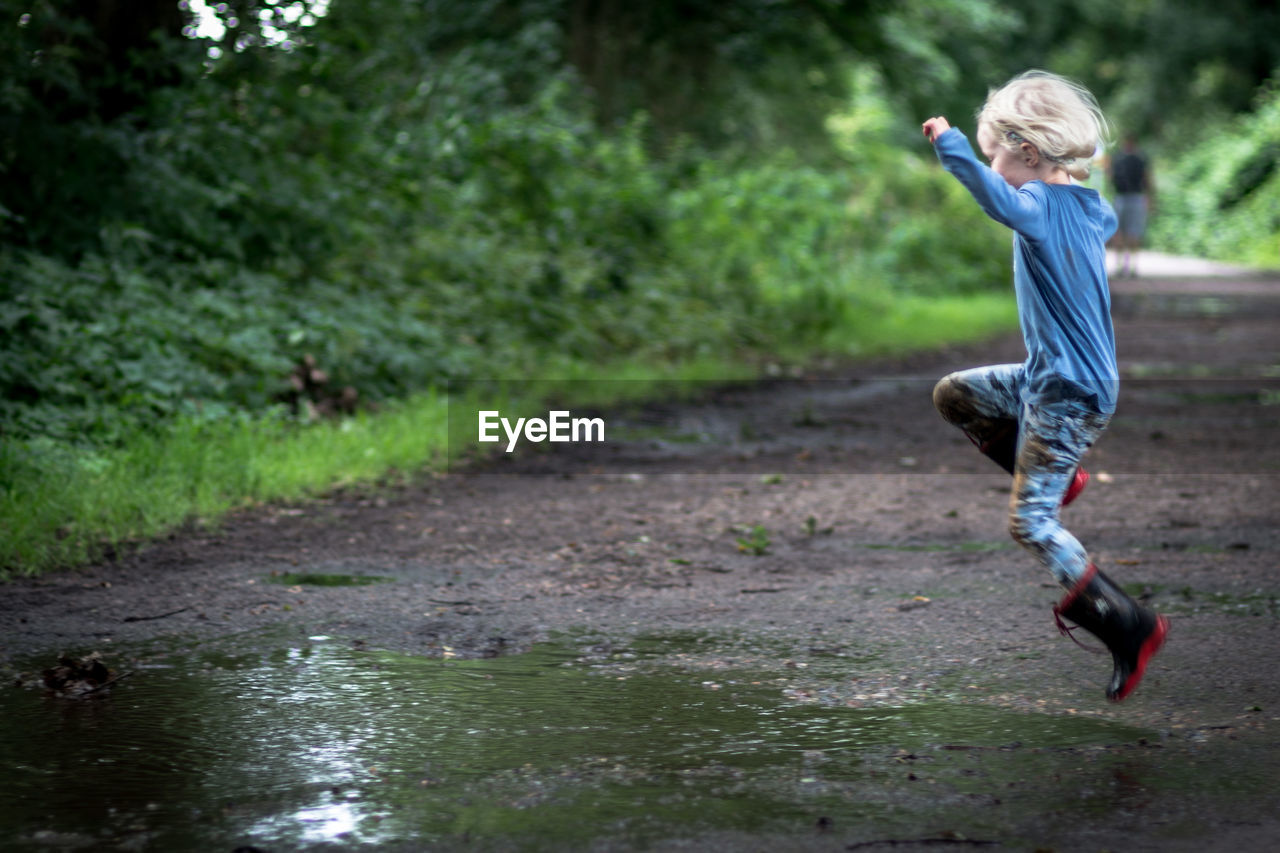 Side view full length of girl playing in puddle