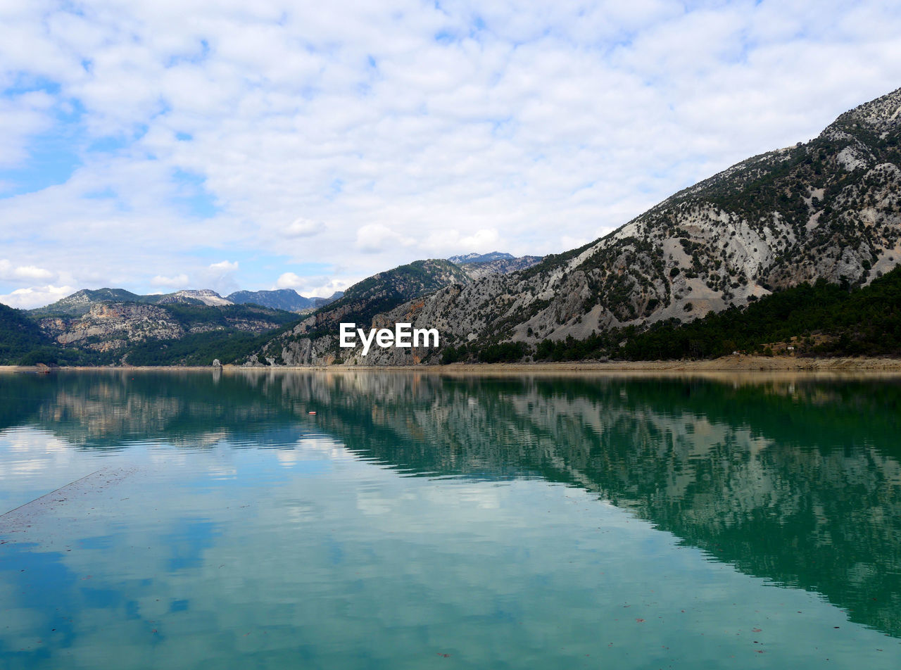 Scenic view of lake and mountains against cloudy sky