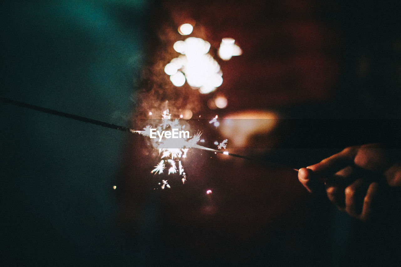 Close-up of man holding firework display at night