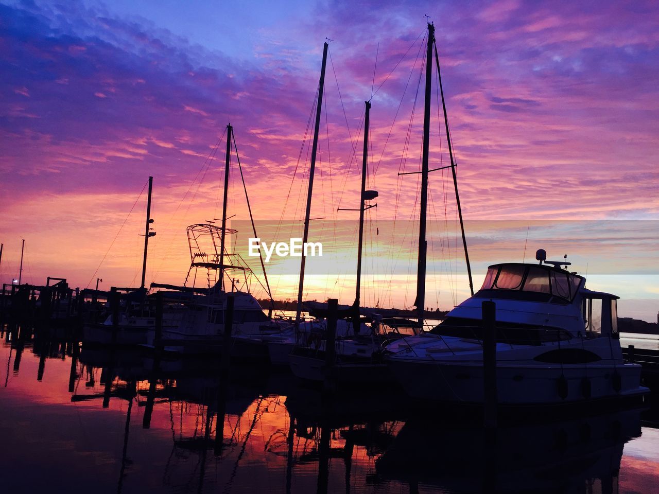 Boats moored in harbor during sunset