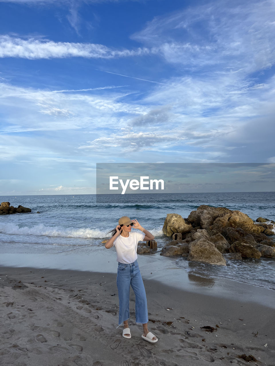 rear view of young woman standing at beach against sky