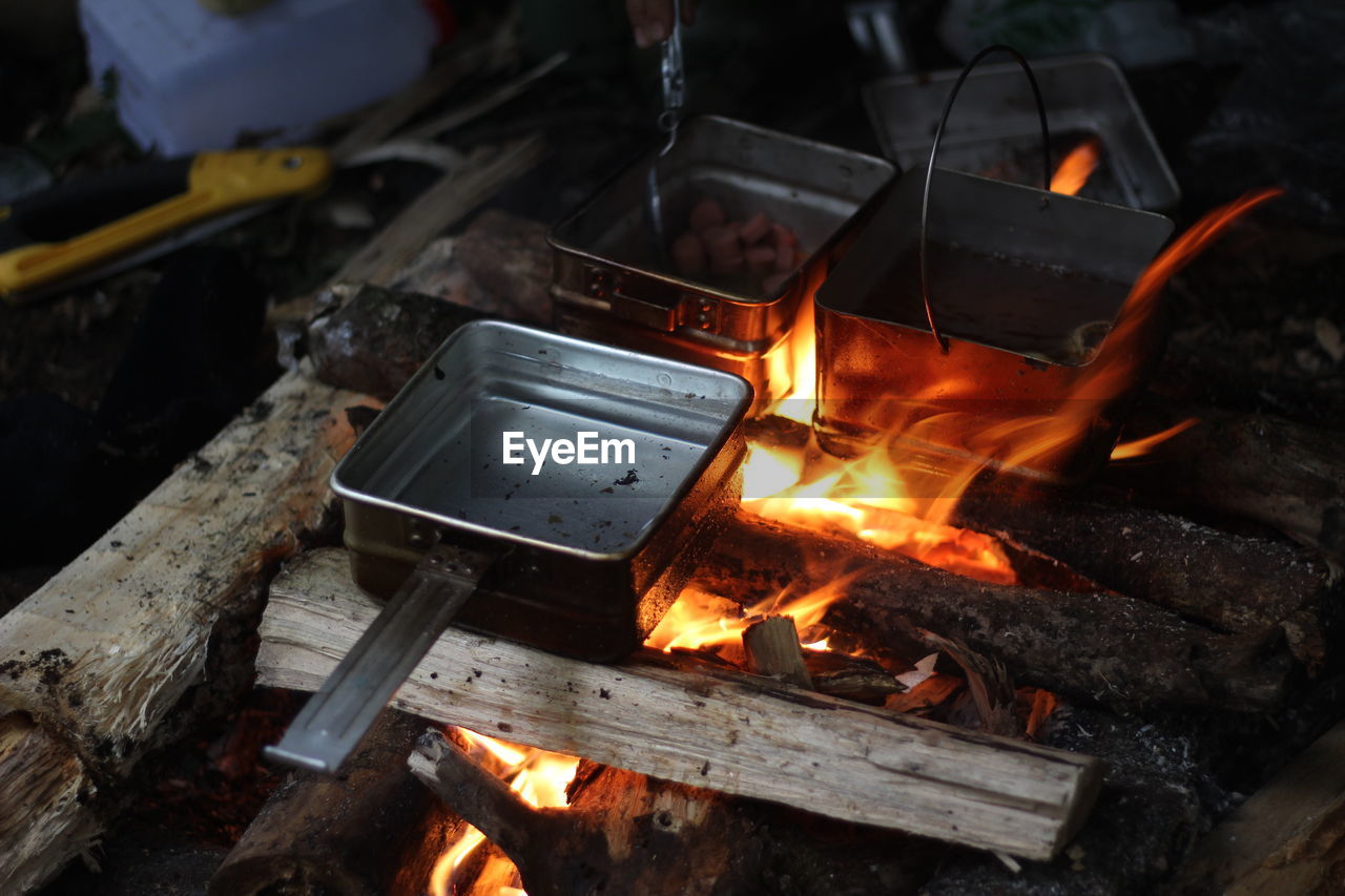 Cooking food in the forest using firewood in a box-shaped frying pan.