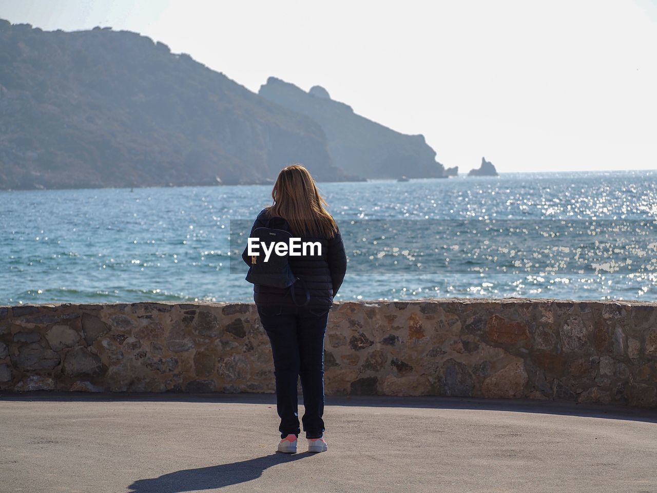 REAR VIEW OF WOMAN LOOKING AT SEA