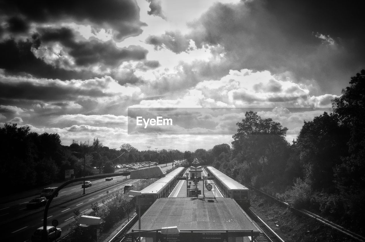 Trains at railroad station by road against sky