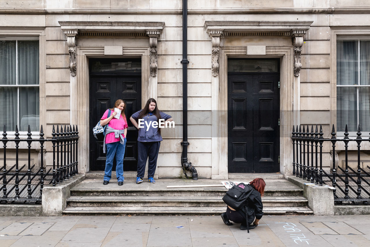 FULL LENGTH OF COUPLE STANDING AGAINST BUILDING IN CITY