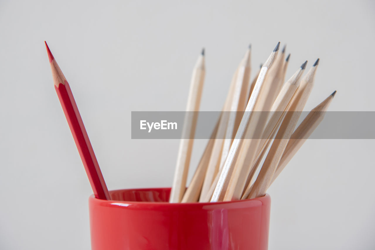 CLOSE-UP OF RED PENCILS ON WHITE SURFACE