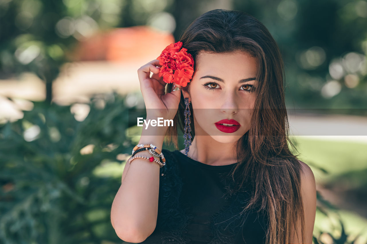 Portrait of beautiful young woman wearing red flower