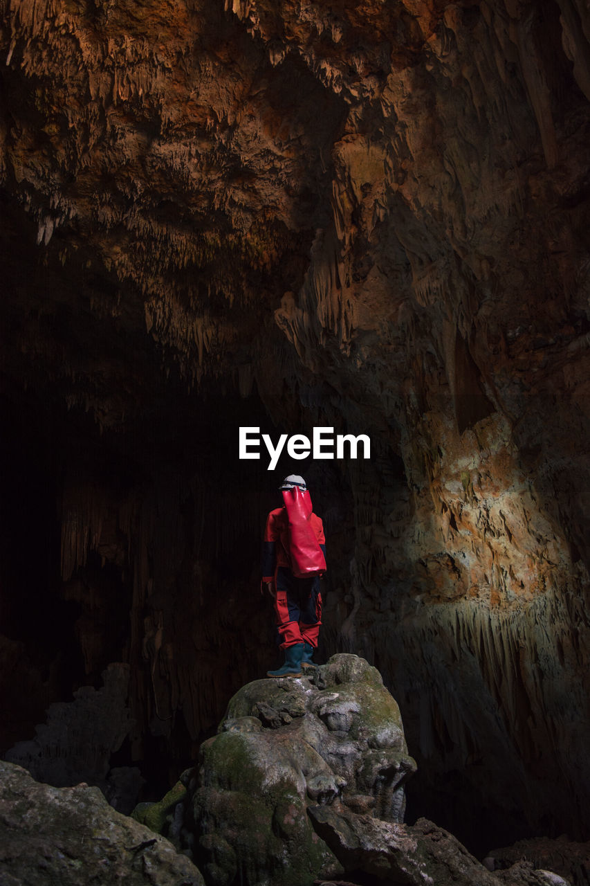 Rear view of man standing on rock in cave