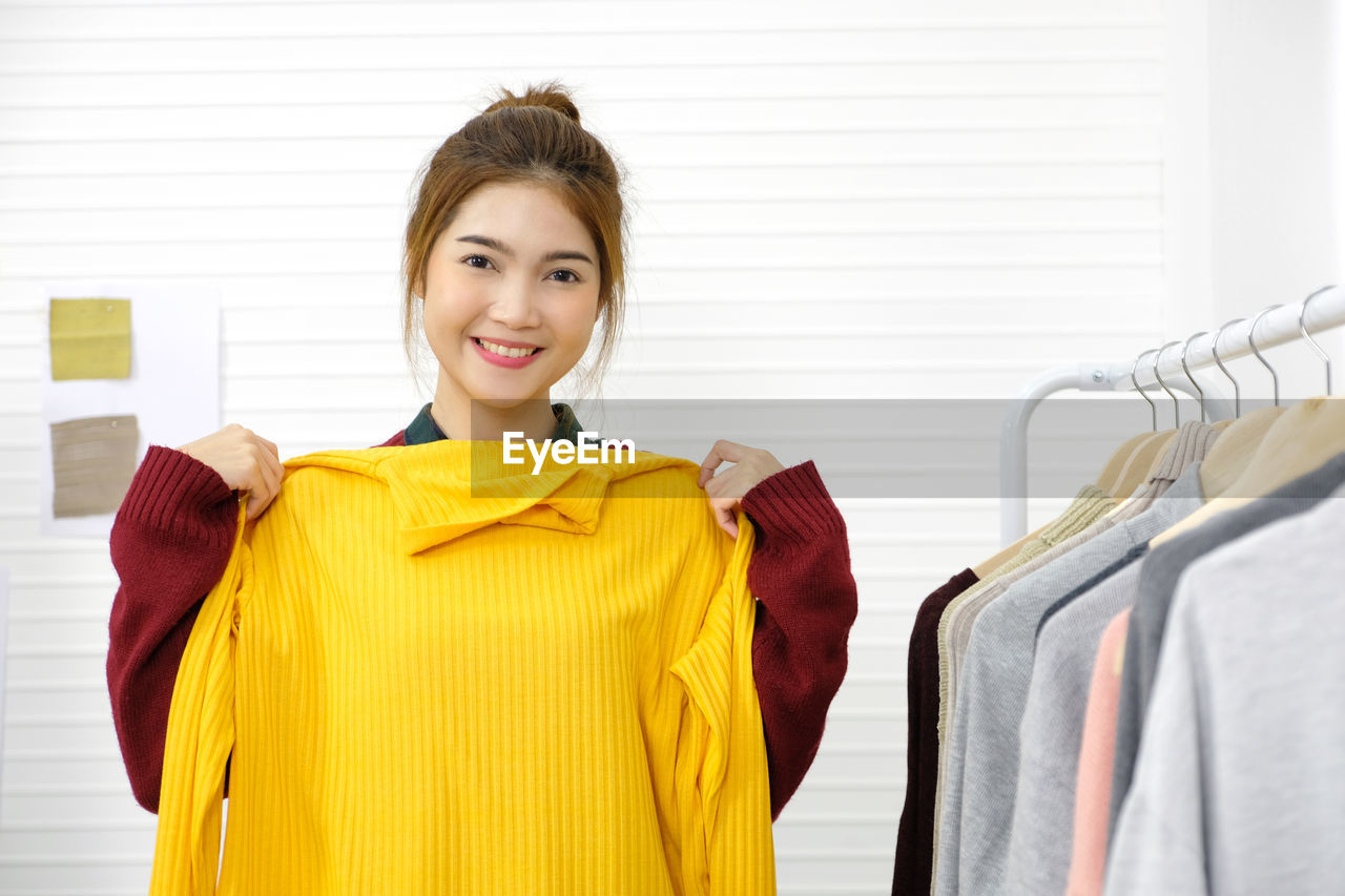 PORTRAIT OF A SMILING YOUNG WOMAN STANDING AGAINST STORE