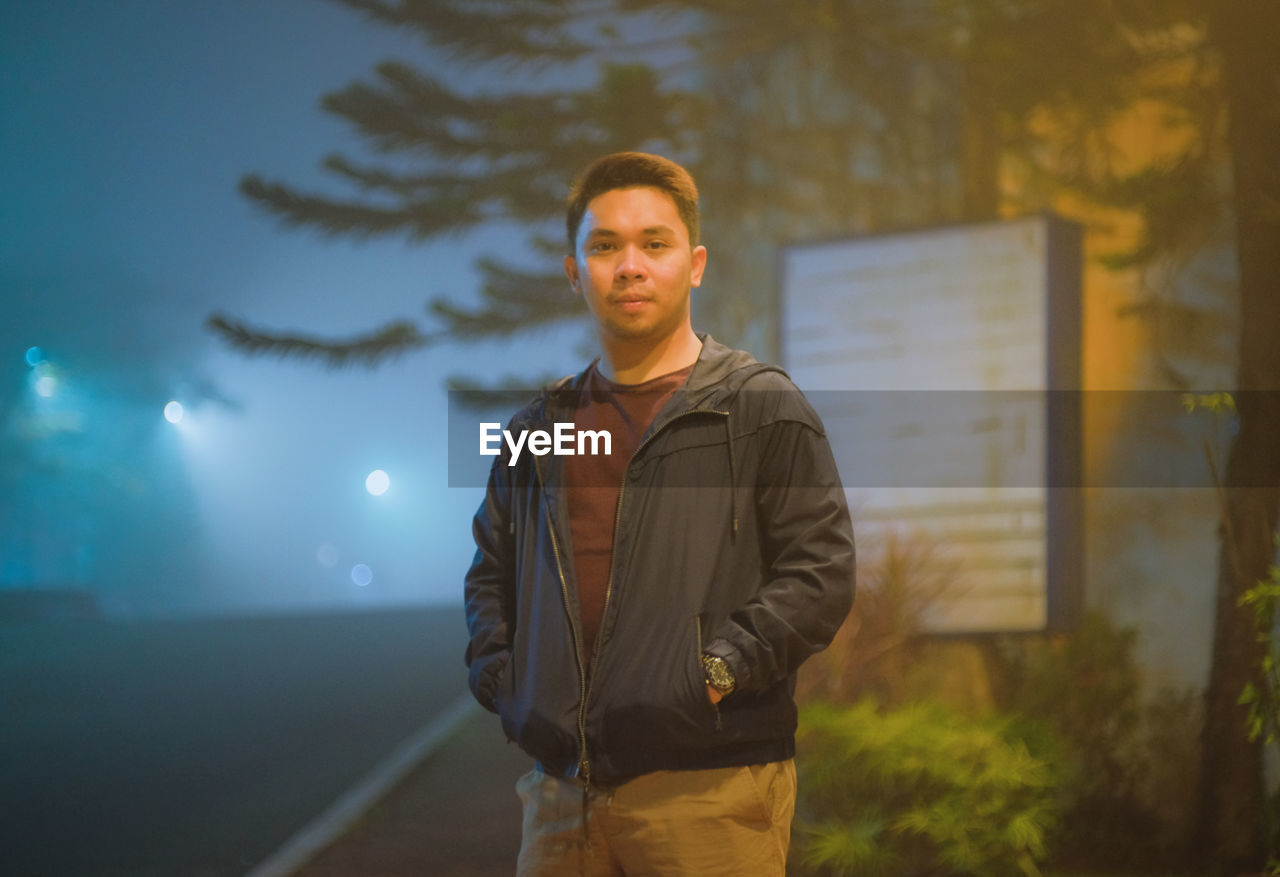 Portrait of young man standing outdoors at night