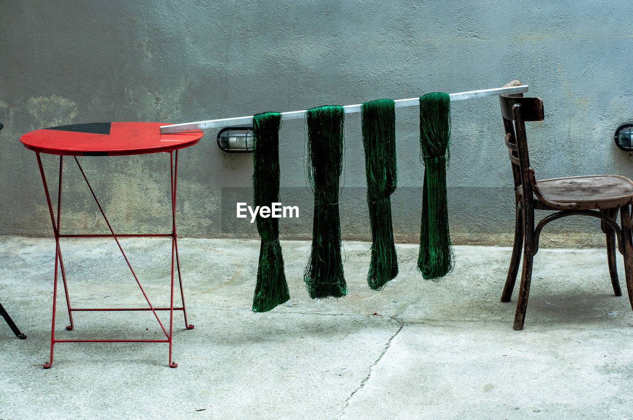 Dyed hand knitting yarn is hanged to dry between a table and a chair.